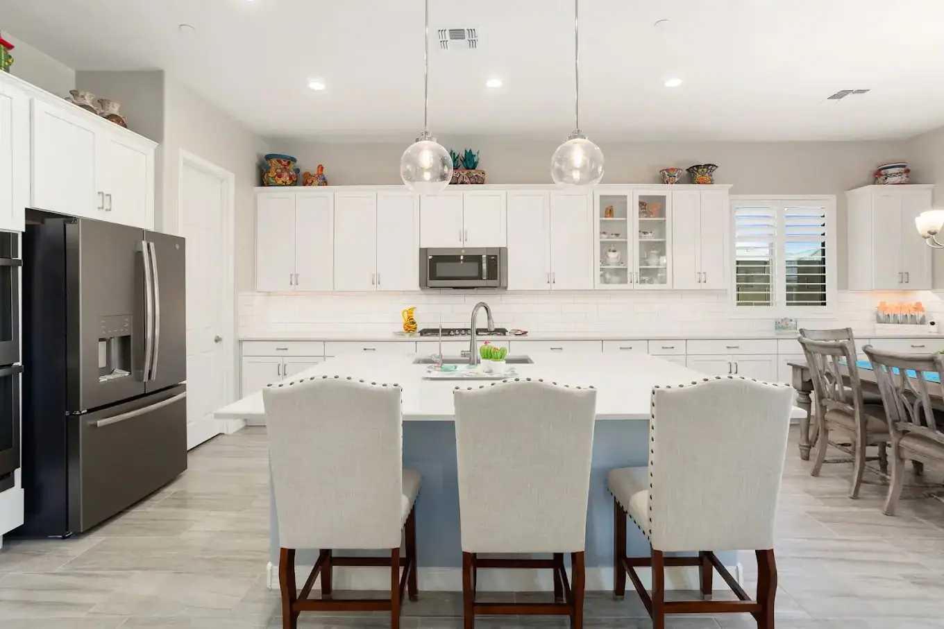 White kitchen with a blue island and bar stools in a home covered by the Arizona Buyers Guide