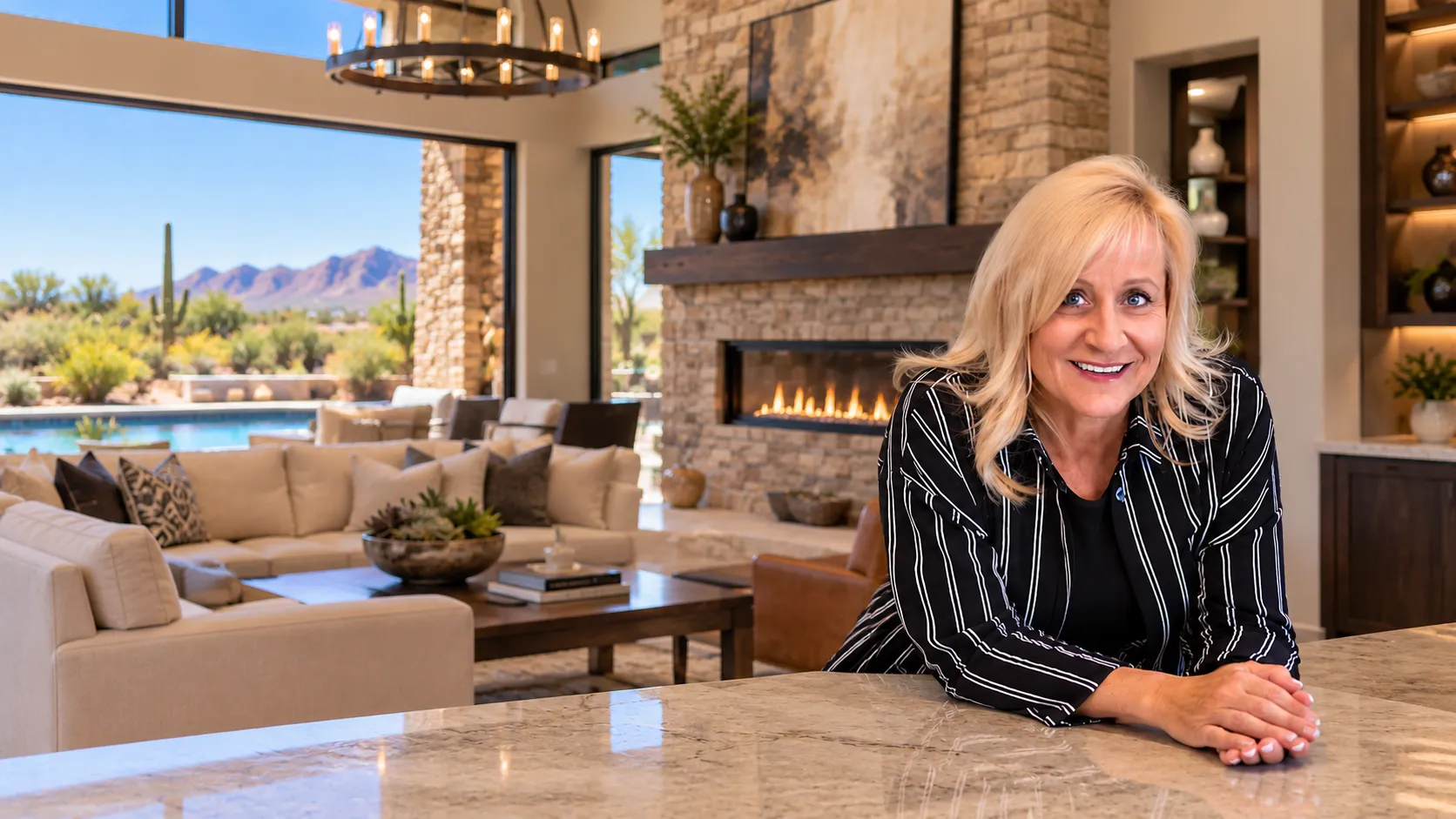 Deah Hendriksz, Realtor, smiling in a living room with a fireplace and a view of the pool and mountains