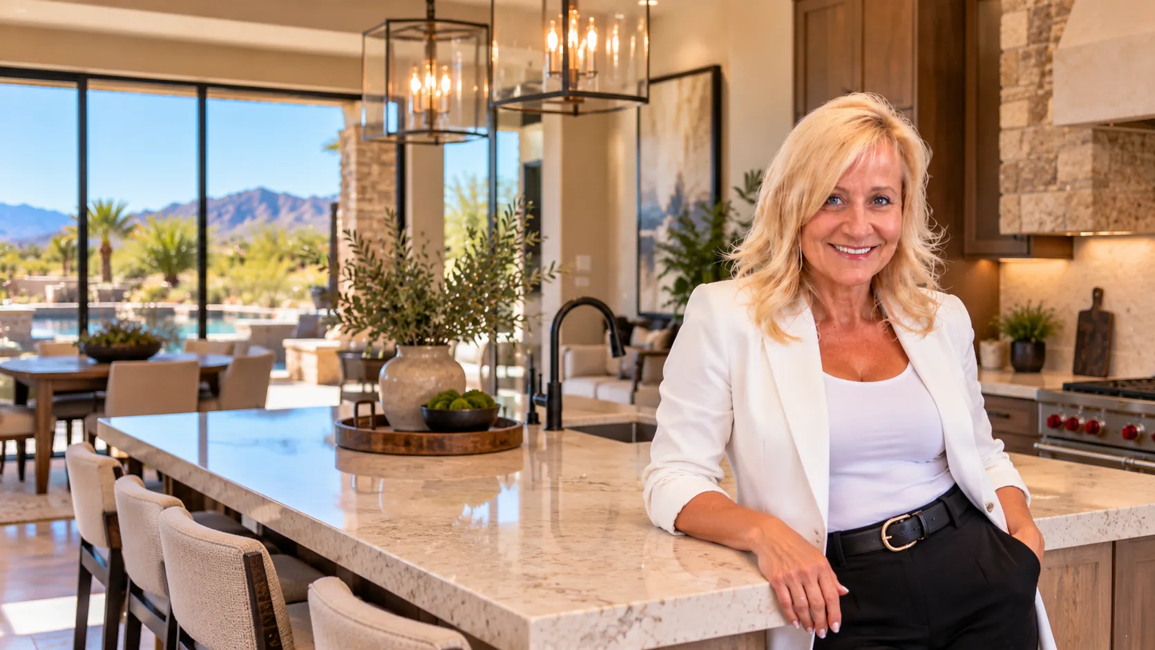 Deah Hendriksz, a Litchfield Park AZ Realtor, standing at a marble kitchen island in a bright home with mountain views