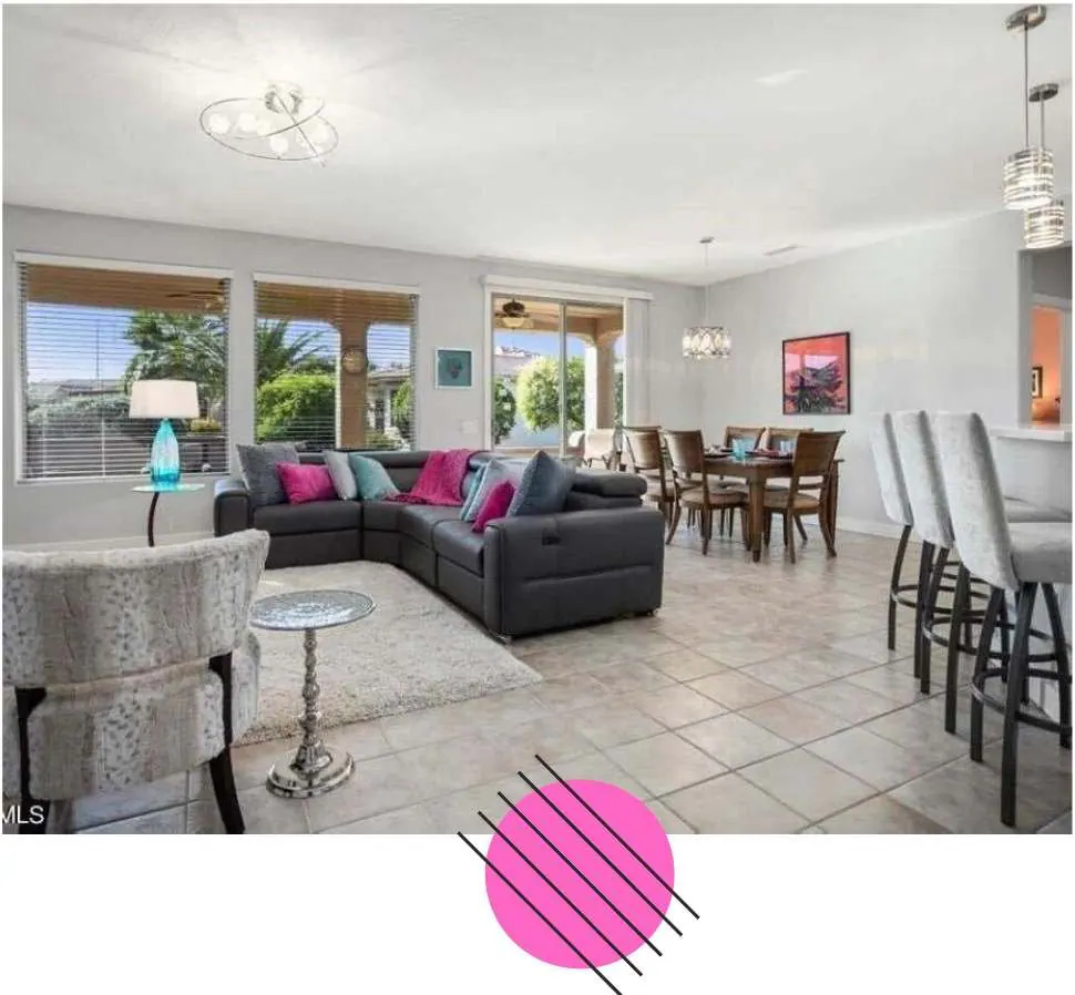 Living room with a dark sectional sofa, tile floors and a view of the dining area